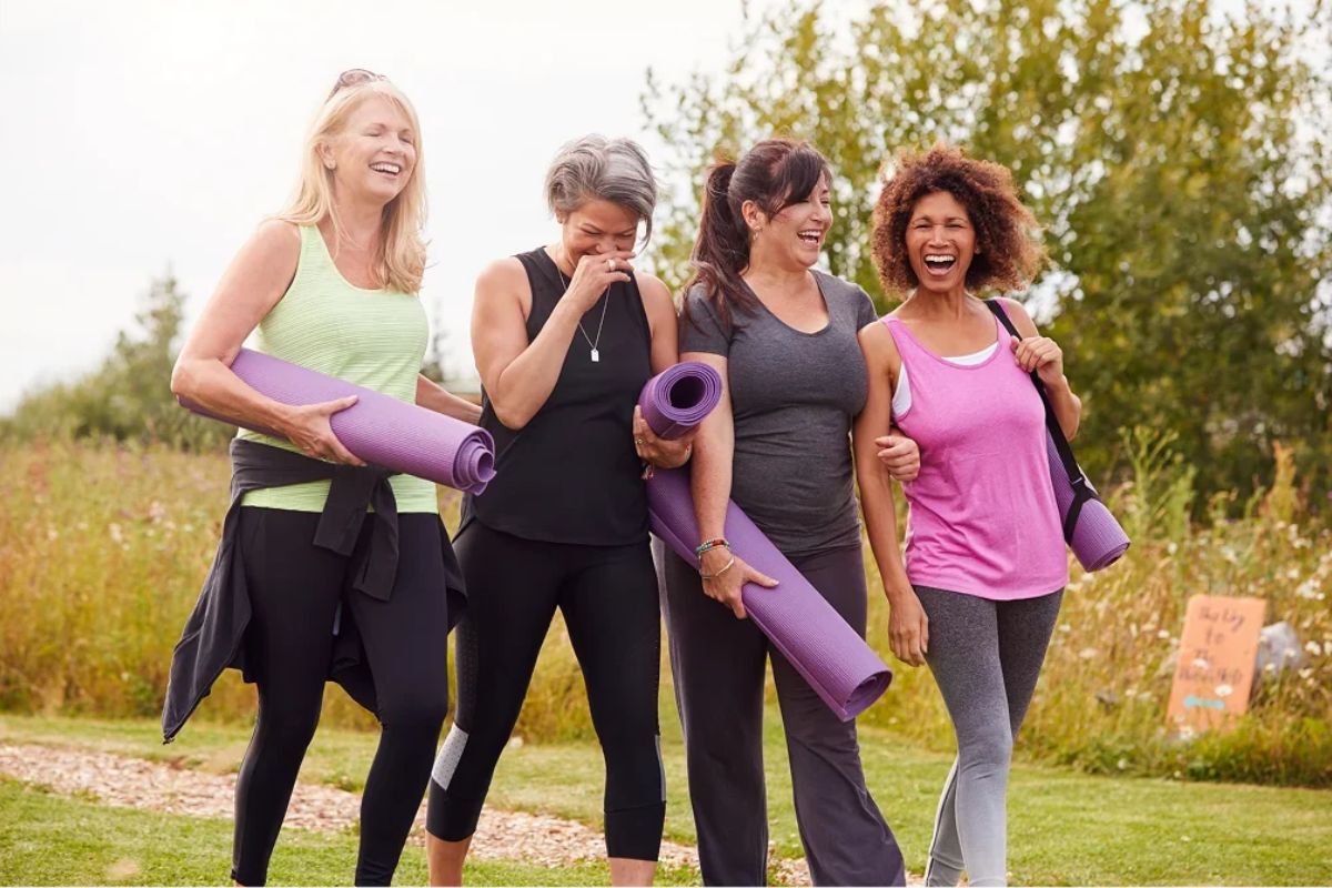 HonorHealth Whole Health institute - Group of female Integrative and Lifestyle Medicine patients walk in park with yoga mats after exercise session.
