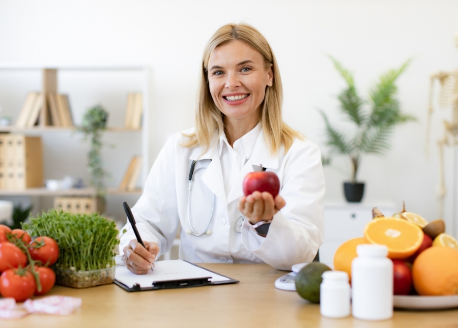 HonorHealth Healthy Living - Doctor smiles at desk holding apple