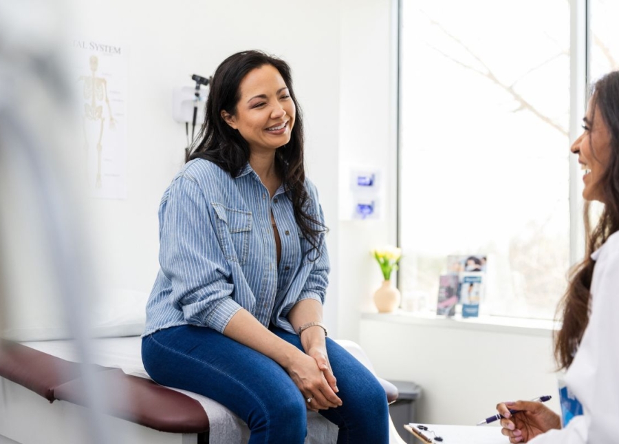 Woman smiles on physician table at a Well Women's visit at HonorHealth Primary Care