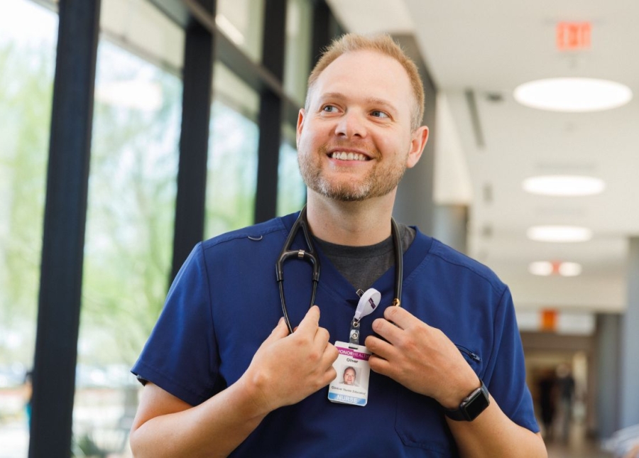 HonorHealth Careers - Smiling nurse walks down hallway with stethoscope around neck.