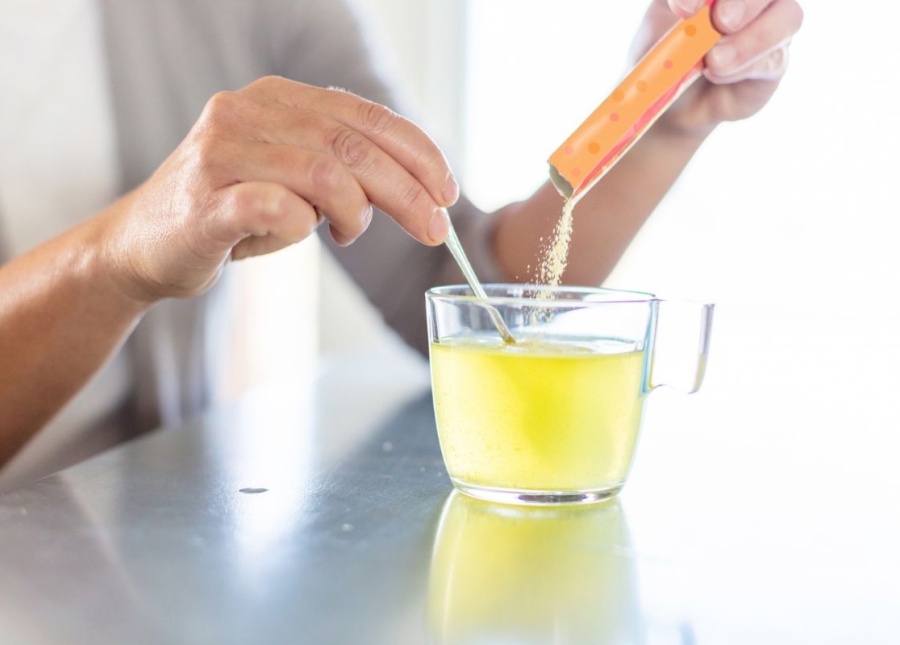 HonorHealth Sports Medicine - Woman pours electrolyte packet into cup of water for hydration.