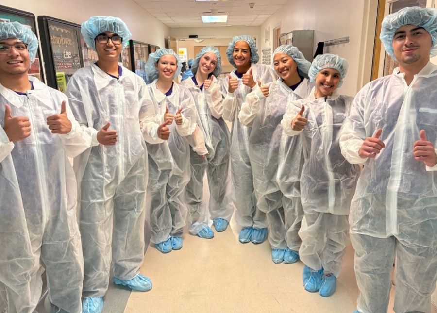 HonorHealth Explorers Club - Group of teen volunteers dressed in operating scrubs smile with thumbs up in group photo.