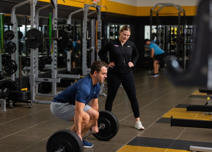 HonorHealth Medical Fitness - Trainer coaches man doing deadlift during strength training session.