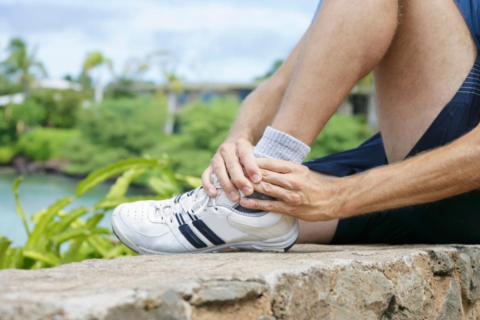 Person holding their ankle in pain from arthritis—relevant to care offered by HonorHealth Orthopedics.