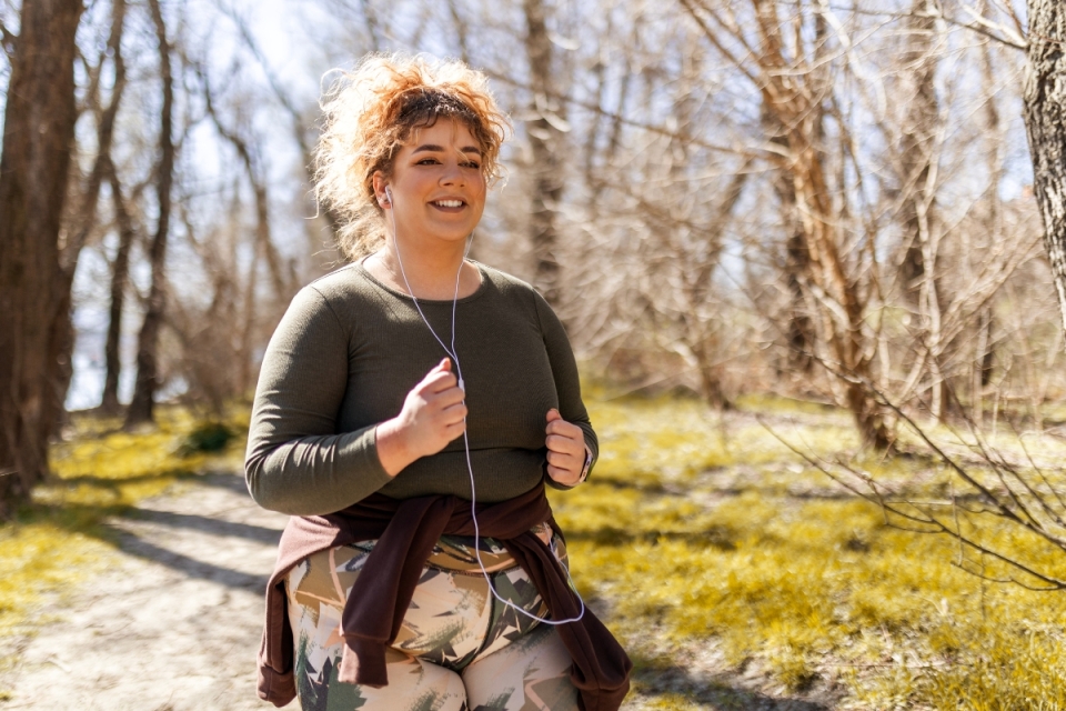 A woman jogs outdoors, smiling and listening to music — reflecting HonorHealth’s holistic, science-backed approach to weight management and wellness.