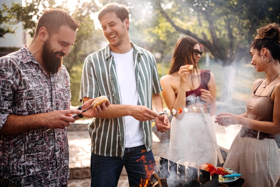 Group of friends practice grilling safety tips while enjoying a summer day outside.