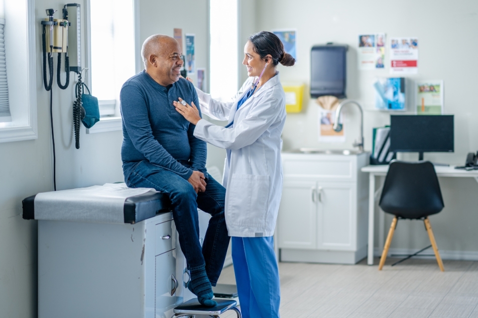 HonorHealth Primary Care Physician performs check up with stethoscope on male patient.