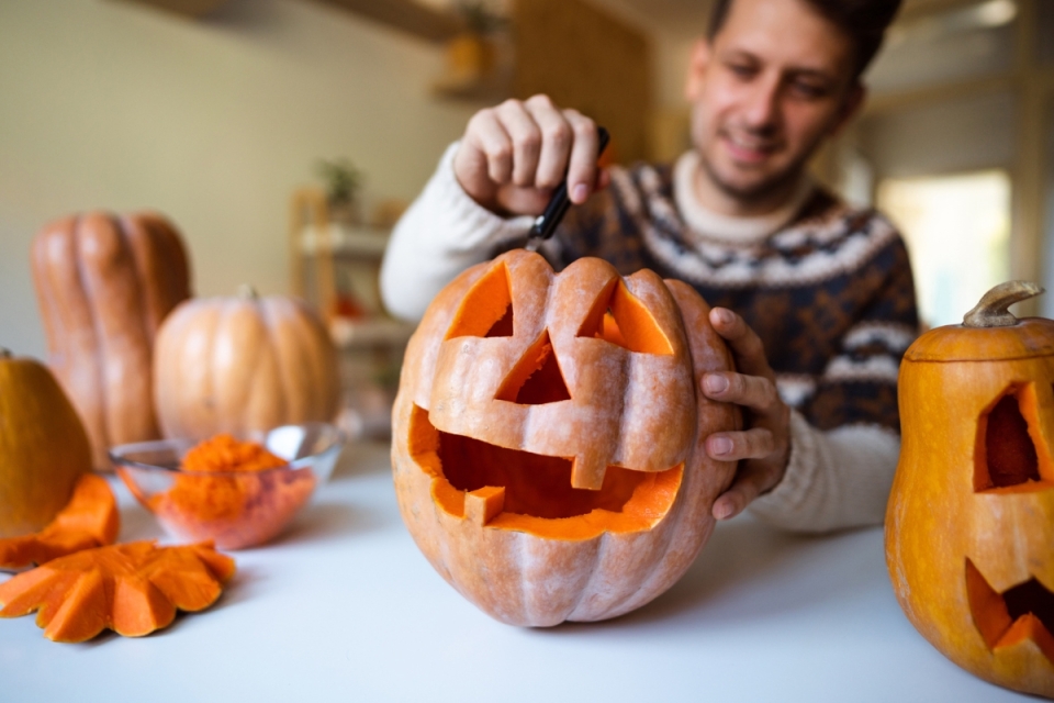 Man happily carves pumpkin with smile on face.