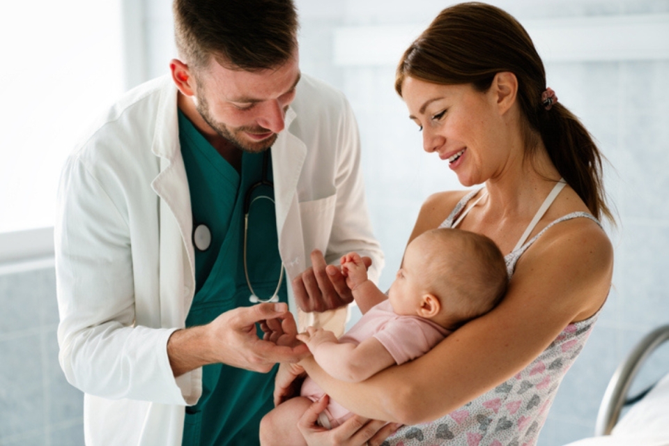 HonorHealth provider gently examines an infant while a parent holds the baby during a pediatric visit.