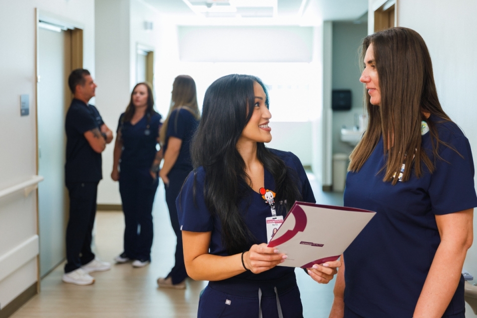 HonorHealth nurses collaborate in hallway of hospital.