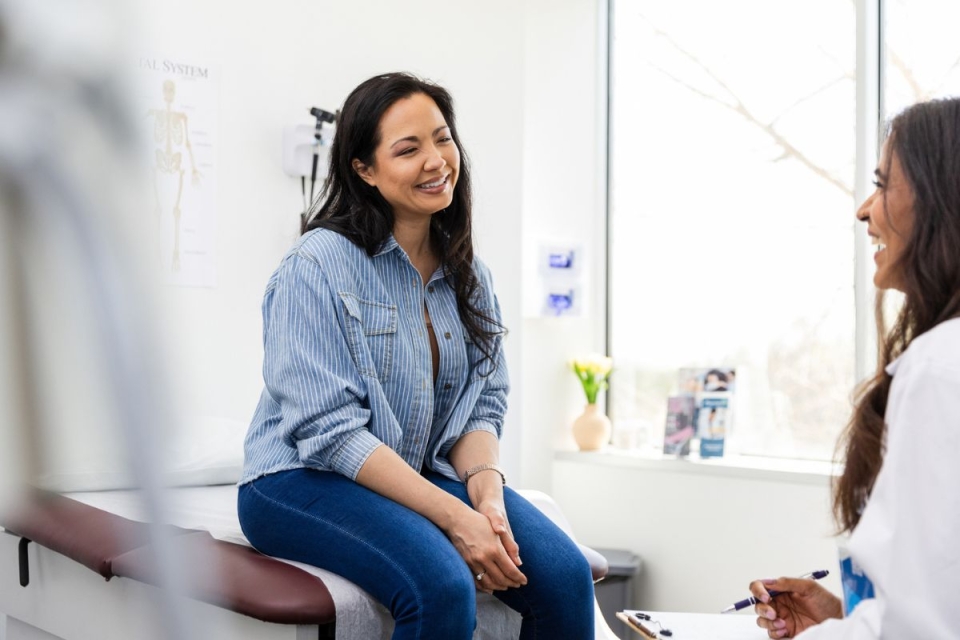 Woman smiles on physician table at a Well Women's visit at HonorHealth Primary Care