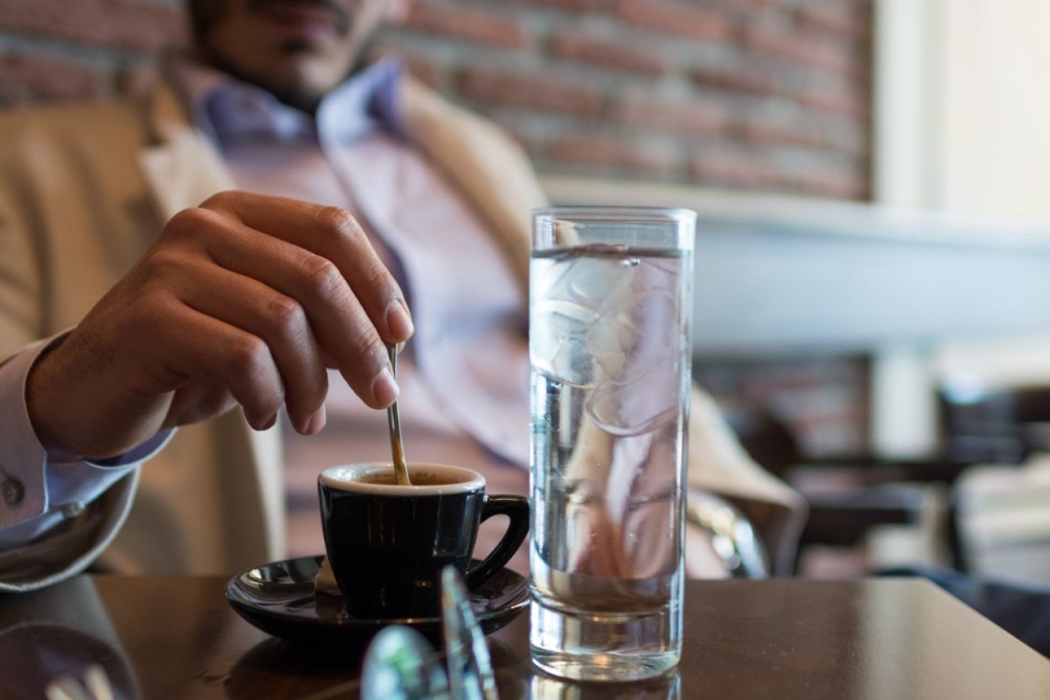 Man drinks glass of water before coffee in the morning, as directed by HonorHealth gastroenterologist.