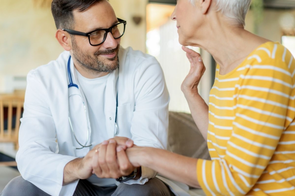 HonorHealth electrophysiology specialist holds the hand of female patient while discussing an implantable heart monitor to prevent stroke.