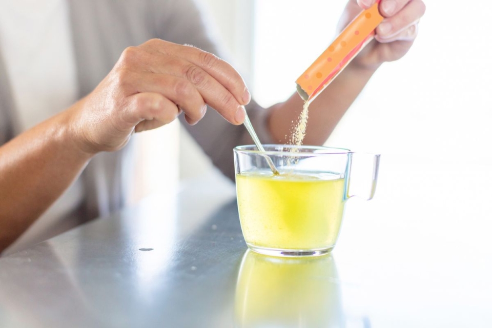 HonorHealth Sports Medicine - Woman pours electrolyte packet into cup of water for hydration.