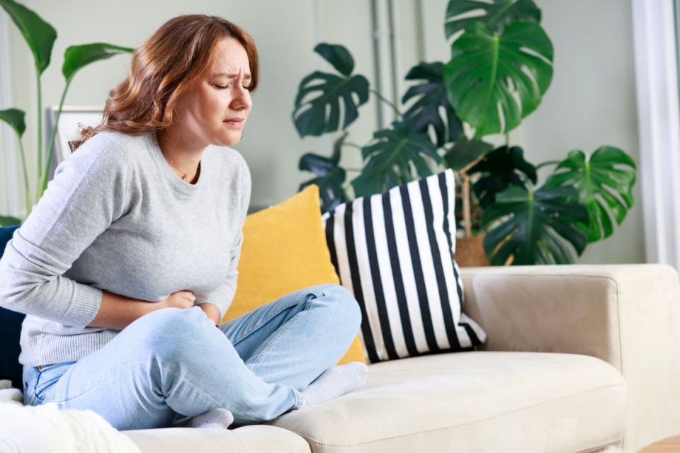 HonorHealth Gynecology - Woman holds abdomen in pain from uterine fibroids.