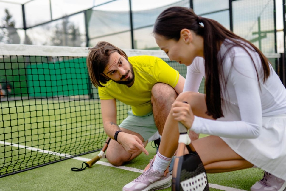 HonorHealth non-operative sports medicine - Coach sits with woman on court after a pickleball injury.
