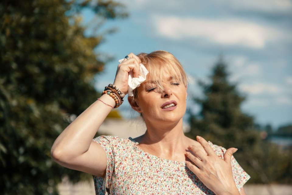 Woman wiping sweat from her forehead in extreme Arizona heat, illustrating symptoms of heat illness - HonorHealth Urgent Care