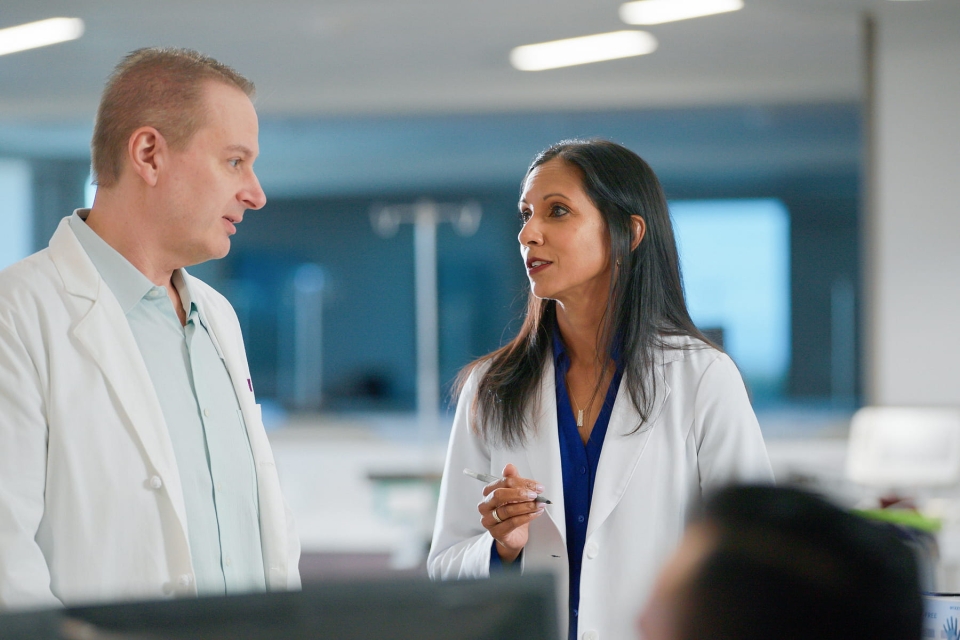Two HonorHealth physicians wearing white lab coats in discussion in a healthcare setting.