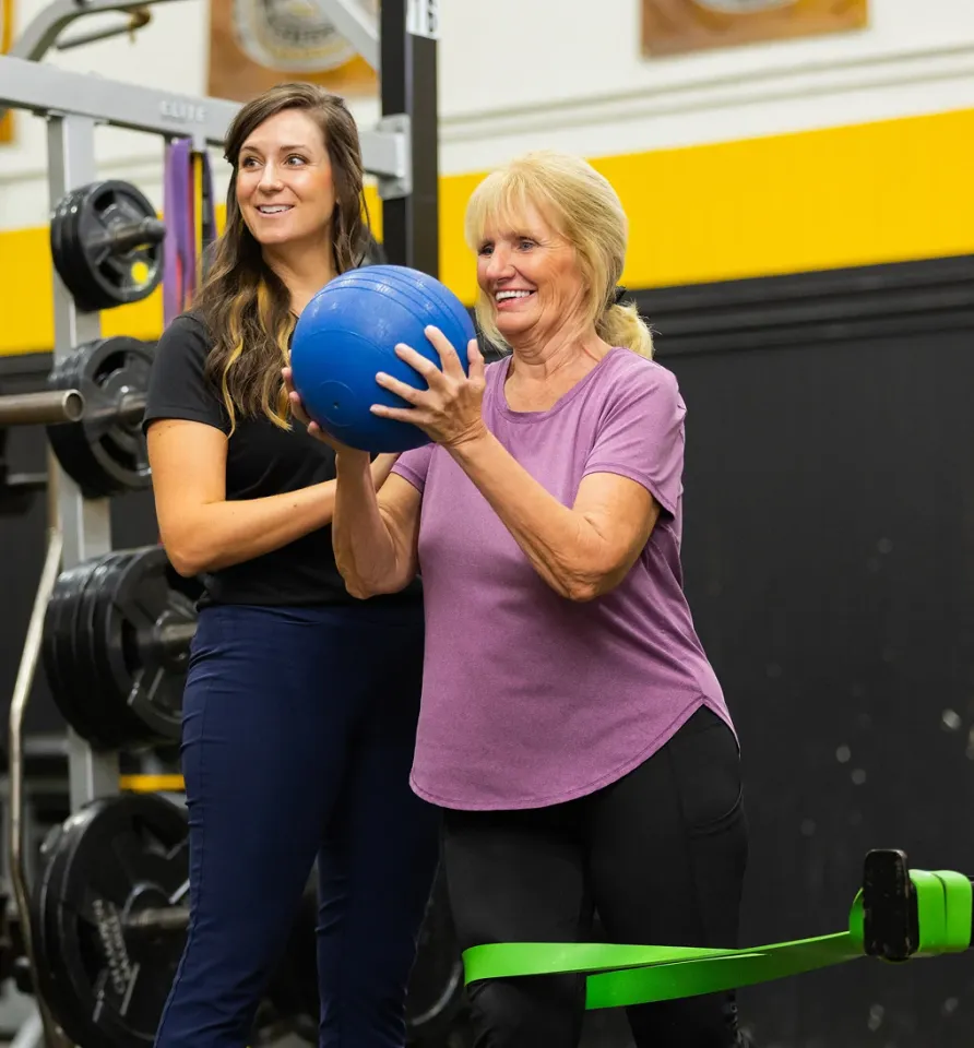 HonorHealth Medical Fitness trainer assists older woman during exercise.