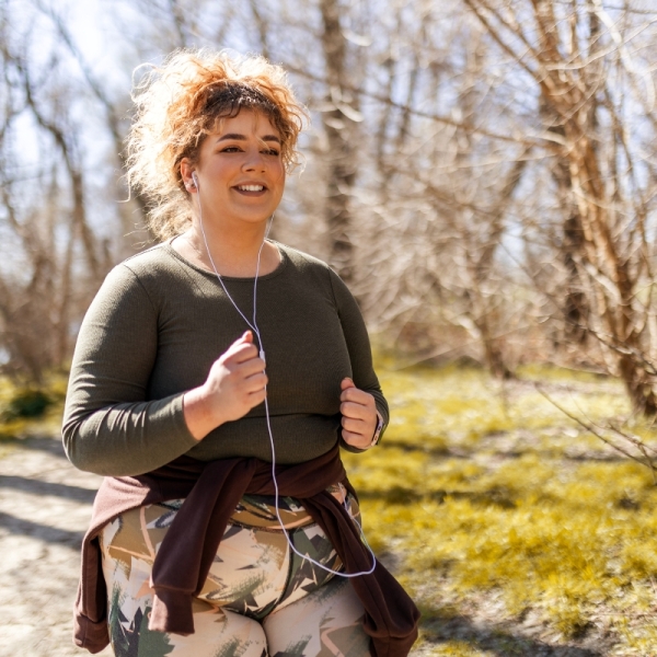 A woman jogs outdoors, smiling and listening to music — reflecting HonorHealth’s holistic, science-backed approach to weight management and wellness.