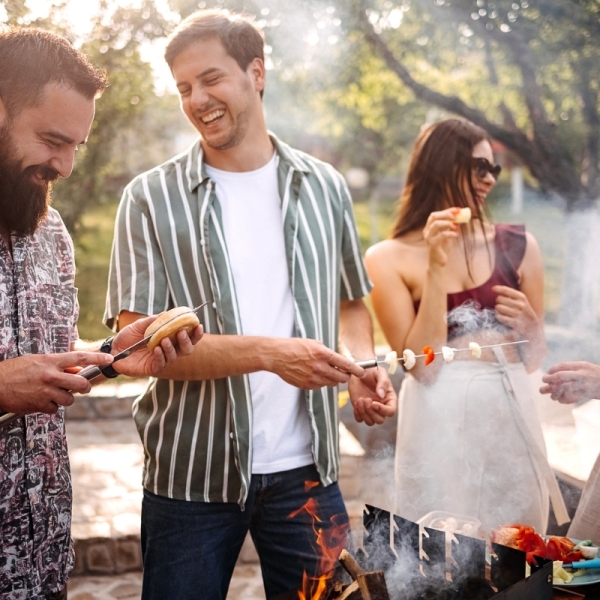 Group of friends practice grilling safety tips while enjoying a summer day outside.