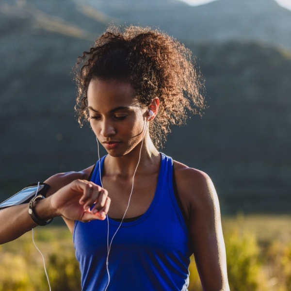 HonorHealth Heart Care - Woman in field looks at smart watch mid-walk trying to reach 10,000 steps.