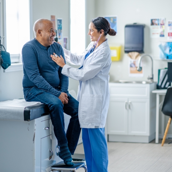 HonorHealth Primary Care Physician performs check up with stethoscope on male patient.