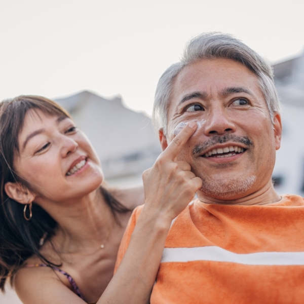 HonorHealth Dermatology - Woman rubs sunscreen onto man's face to prevent skin cancer.