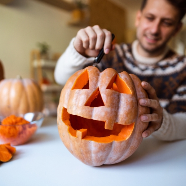 Man happily carves pumpkin with smile on face.