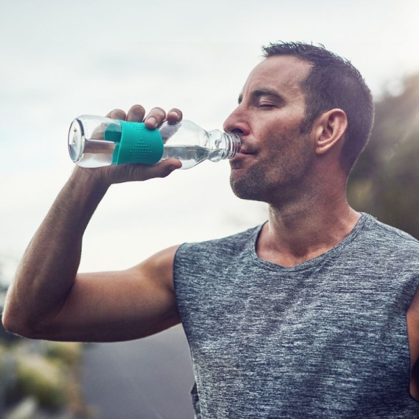 Man takes drink from water bottle outside mid-run - HonorHealth Sports Medicine