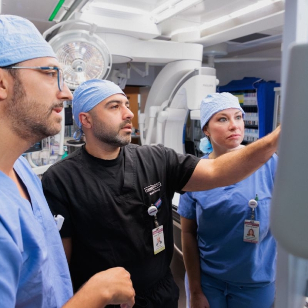 Three HonorHealth Heart Care clinicians in surgical attire reviewing vascular imaging together.