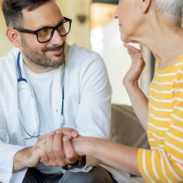 HonorHealth electrophysiology specialist holds the hand of female patient while discussing an implantable heart monitor to prevent stroke.