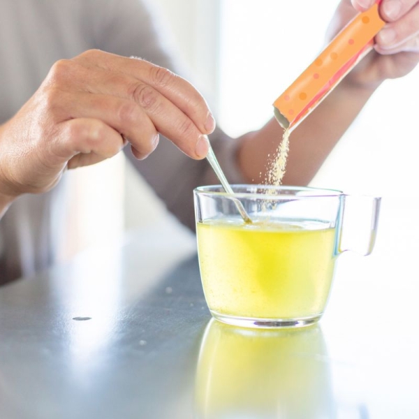 HonorHealth Sports Medicine - Woman pours electrolyte packet into cup of water for hydration.