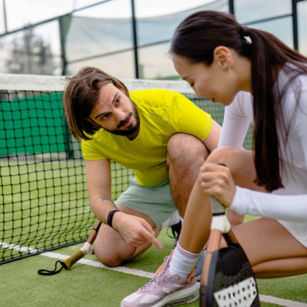 HonorHealth non-operative sports medicine - Coach sits with woman on court after a pickleball injury.