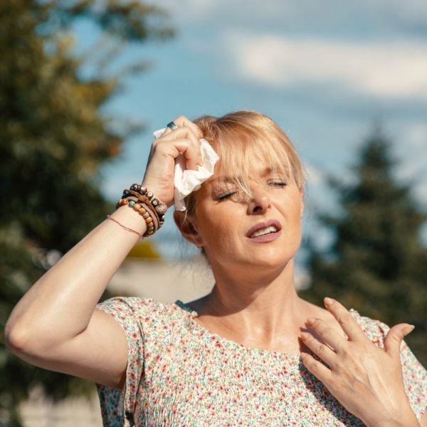 Woman wiping sweat from her forehead in extreme Arizona heat, illustrating symptoms of heat illness - HonorHealth Urgent Care