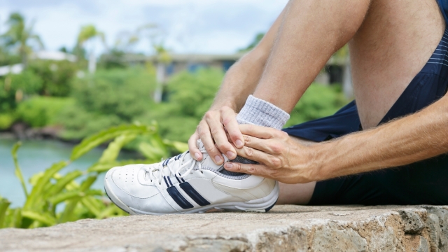 Person holding their ankle in pain, possibly from injury or arthritis—relevant to care offered by HonorHealth Orthopedics.