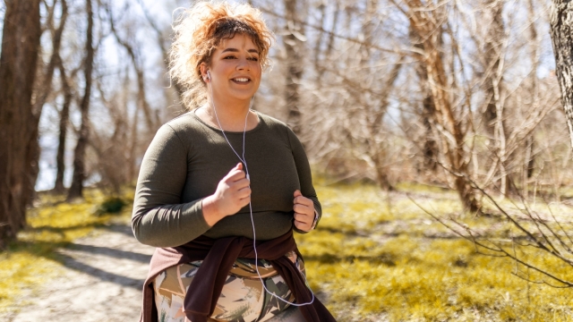 A woman jogs outdoors, smiling and listening to music — reflecting HonorHealth’s holistic, science-backed approach to weight management and wellness.