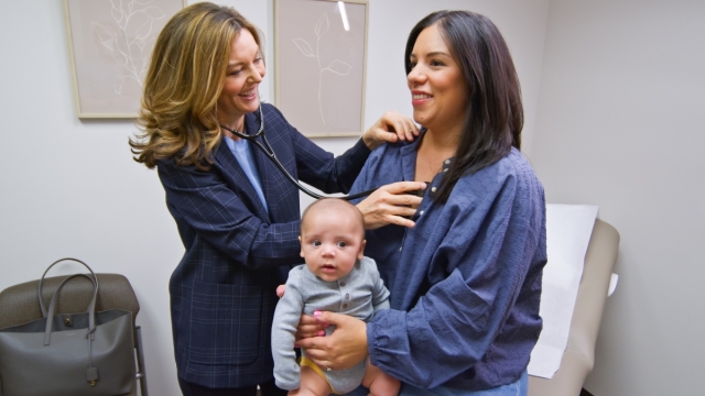 HonorHealth cardiologist, Christina Reuss, MD, takes heart reading for patient holding infant.