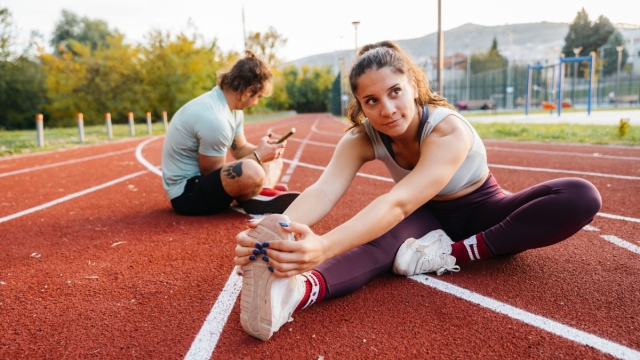 Male and female runners sit on running track and stretch after marathon training - HonorHealth Sports Medicine