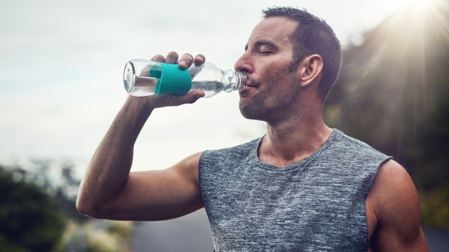 Man takes drink from water bottle outside mid-run - HonorHealth Medical Fitness