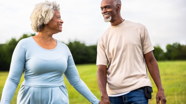 Older couple walking hand in hand outdoors after heart valve treatment, supported by HonorHealth Heart Care.