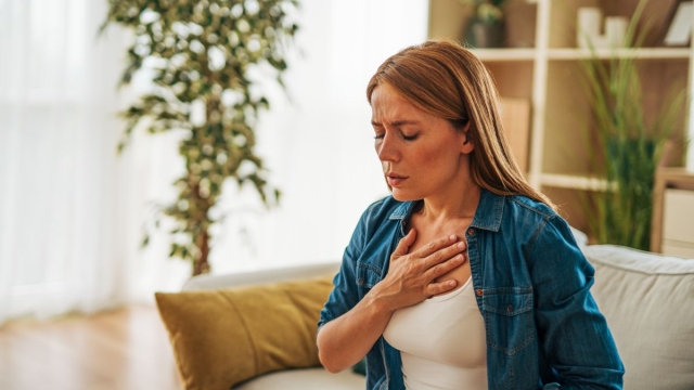 HonorHealth Heart Care - A woman experiencing chest discomfort at home, a common yet often overlooked sign of heart attack in women.
