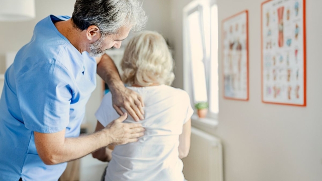 HonorHealth physician uses hands-on manual therapy to address upper back pain in an older patient, illustrating fascial distortion treatment by peeling back tissue layers to relieve stubborn pain.