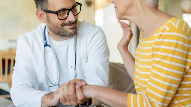 HonorHealth electrophysiology specialist holds the hand of female patient while discussing an implantable heart monitor to prevent stroke.