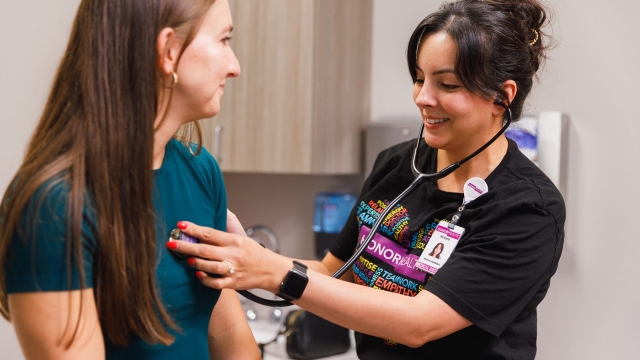 HonorHealth Heart Care - An HonorHealth medical assistant smiling as she places a stethoscope on a patient's chest during an exam.