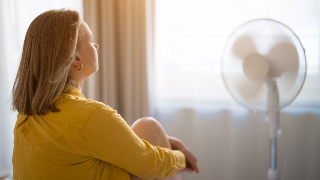 HonorHealth Primary Care - Woman sits in front of fan sitting on bed after a sleepless night due to summer heat.