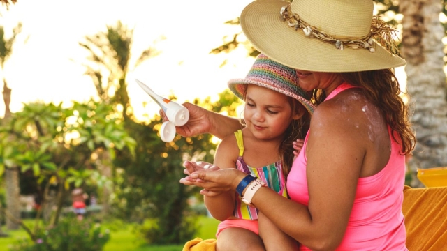 Mother applies sunscreen to her child and herself, using tips from HonorHealth Dermatologist.