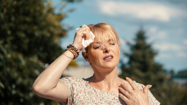 Woman wiping sweat from her forehead in extreme Arizona heat, illustrating symptoms of heat illness - HonorHealth Urgent Care