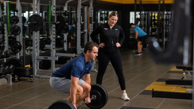 HonorHealth Medical Fitness - Trainer coaches man doing deadlift during strength training session.