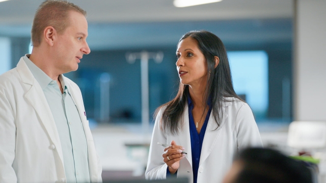 Two HonorHealth physicians wearing white lab coats in discussion in a healthcare setting.